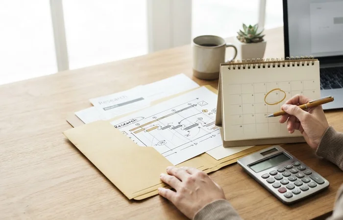 Échéancier fictif dans un dossier, calendrier de bureau et calculatrice.
